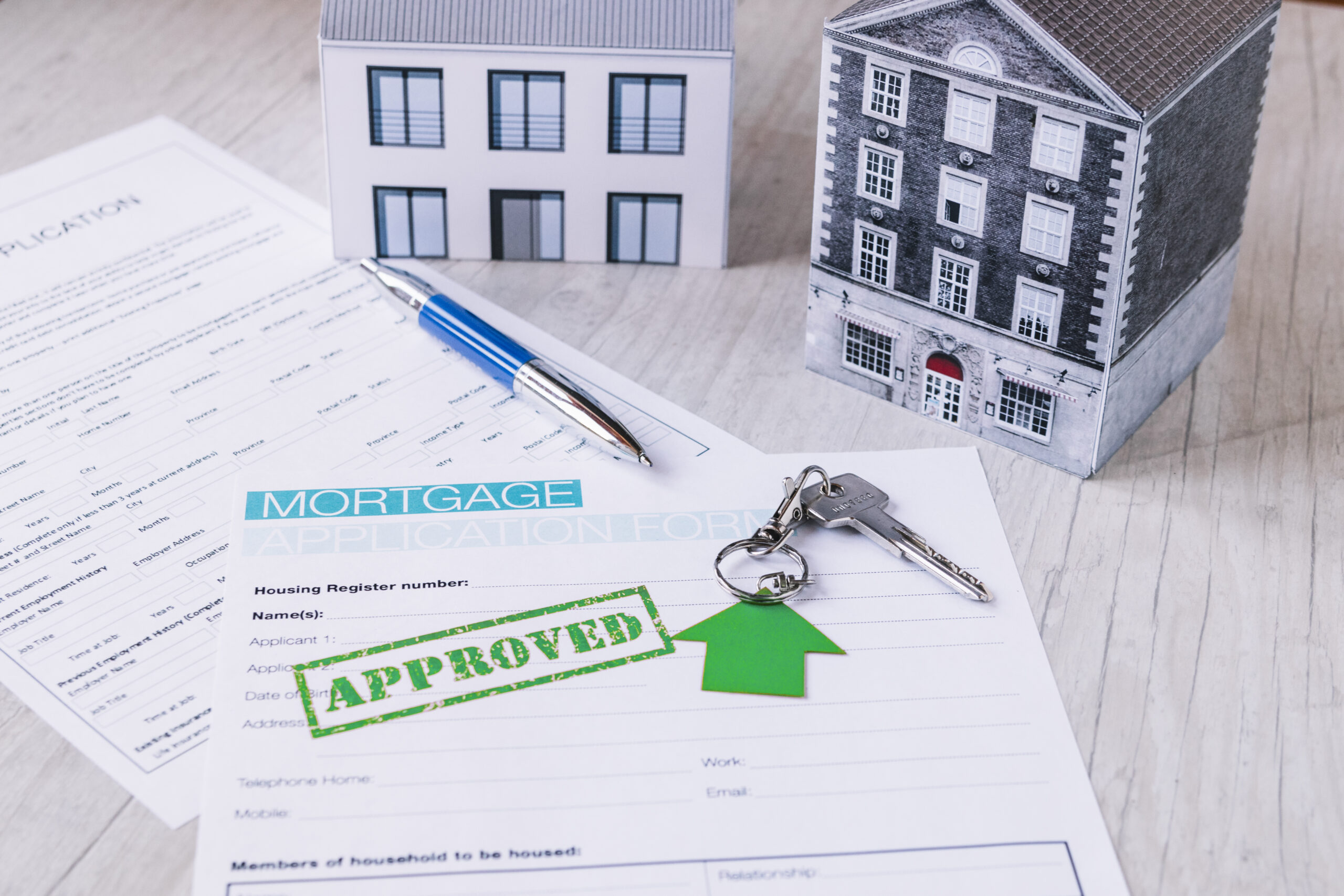 Mortgage application form stamped “APPROVED” with house keys and model homes—symbolizing successful reinvestment into a new multifamily property through a 1031 exchange.