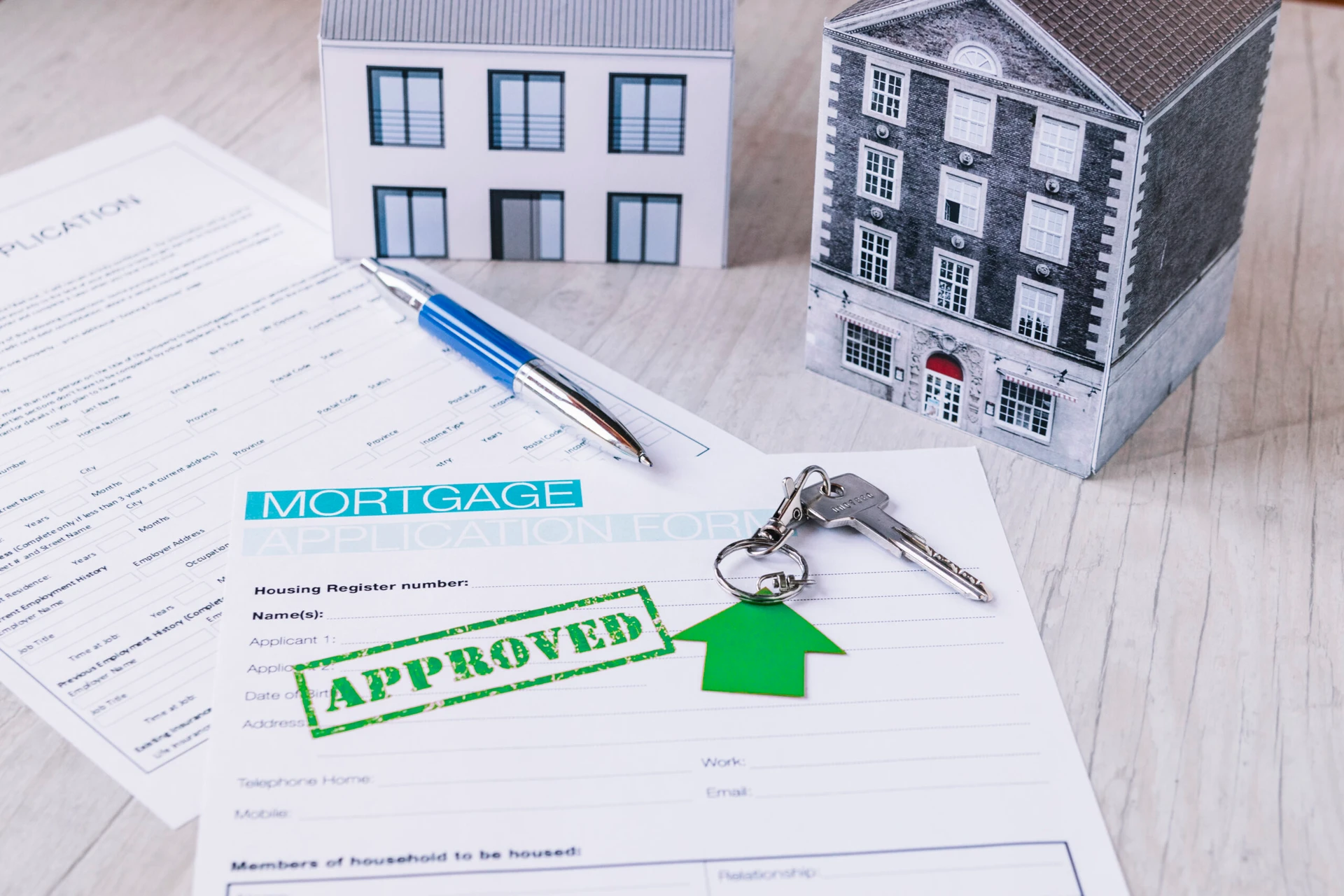 Mortgage application form stamped “APPROVED” with house keys and model homes—symbolizing successful reinvestment into a new multifamily property through a 1031 exchange.